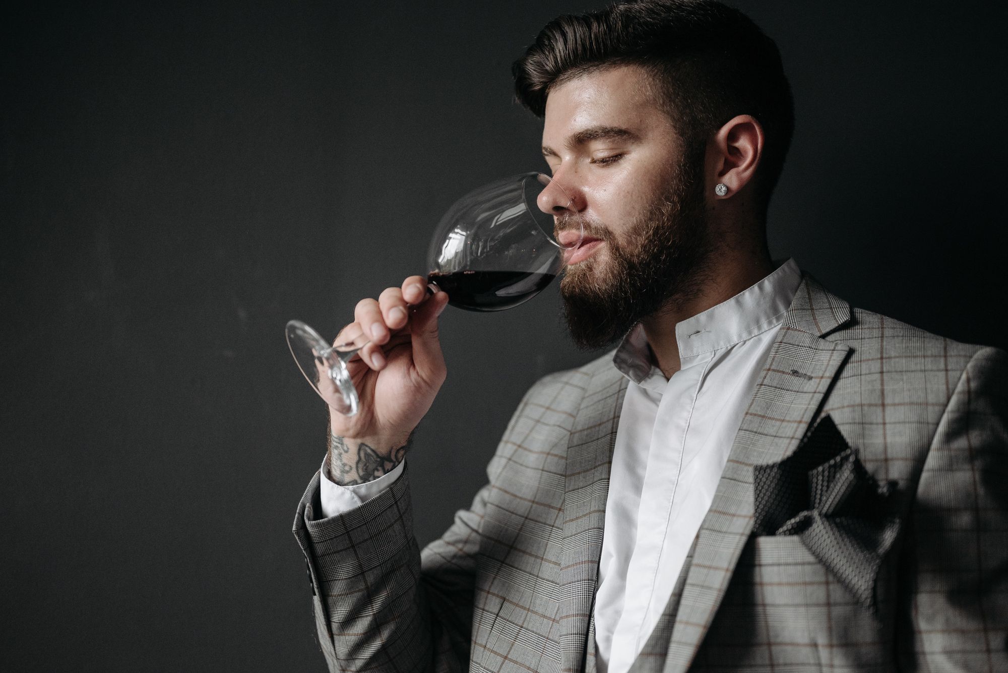 A person holding a wine glass and enjoying the taste of red wine, demonstrating how to drink wine